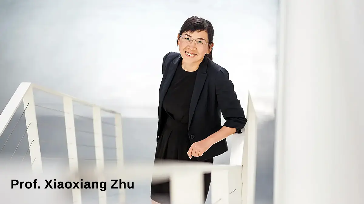 Portrait of Prof. Xiaoxiang Zhu, lead scientist of the Global Building Atlas project, standing on a staircase and smiling