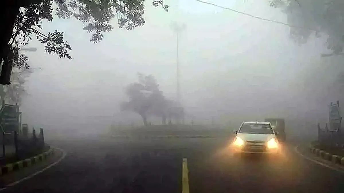 Dense fog covering a road in Hyderabad with a car driving slowly using headlights during severe winter conditions
